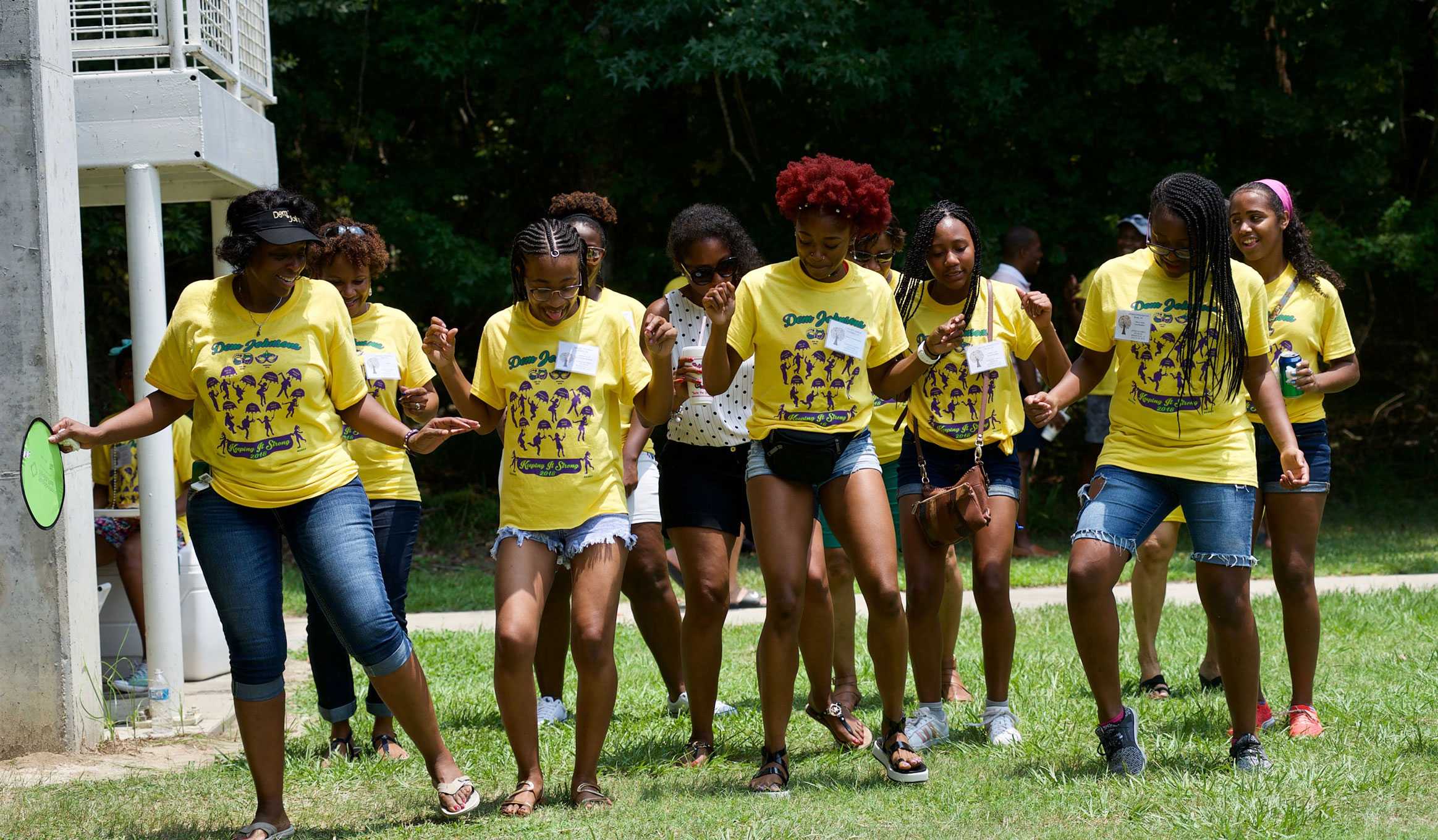 A photo of the Johnson family dancing together in a lawn. They all are wearing yellow shirt.