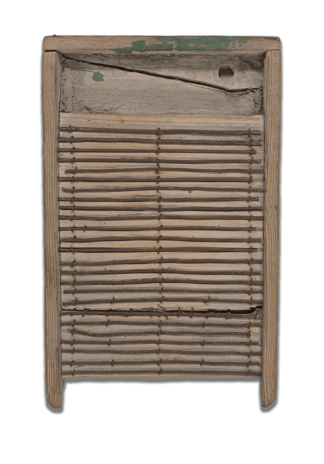 A light colored wooden washboard with a crack at the top and remnants of green paint