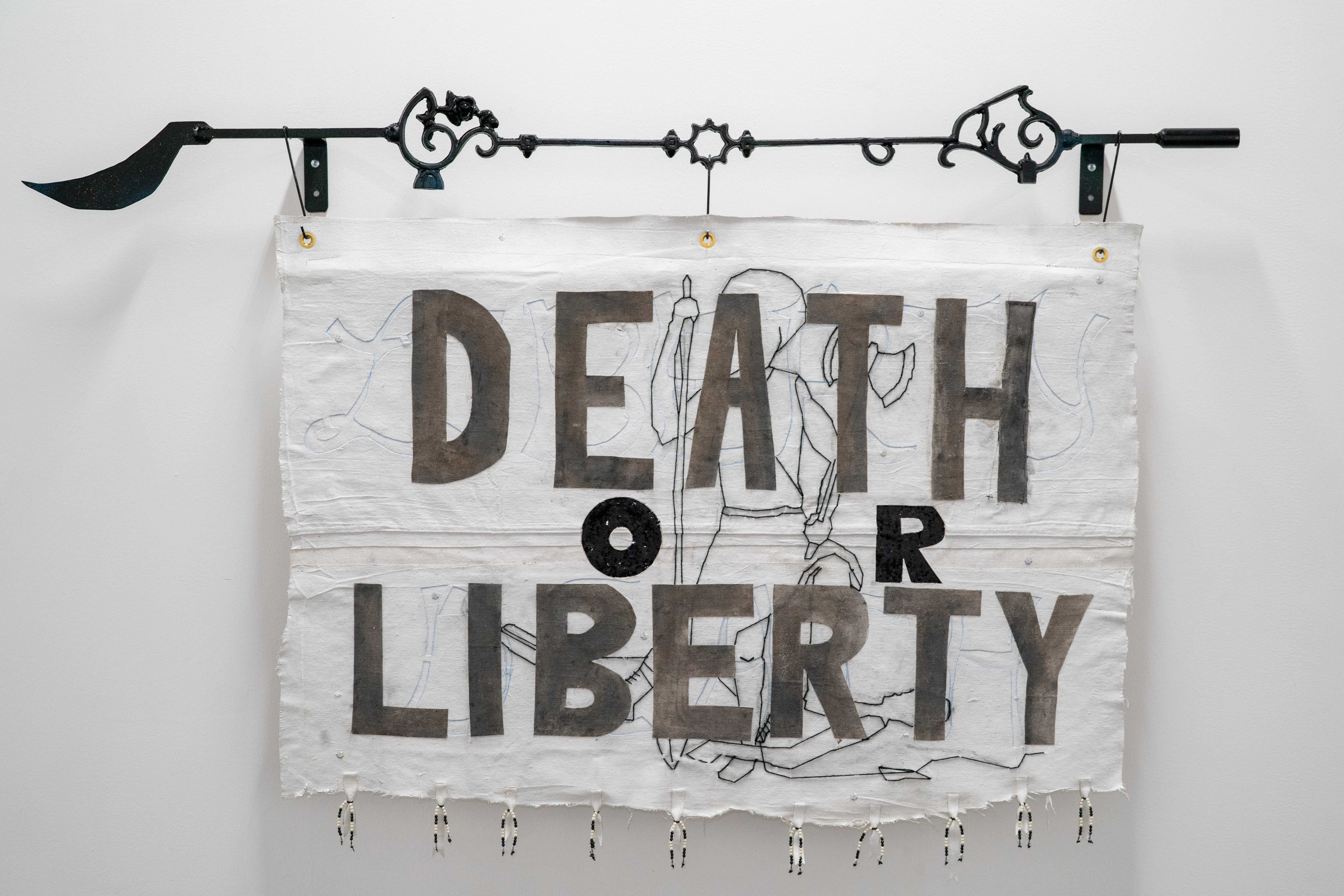 White flag with "Death or Liberty" written on it, hanging from a decorative steel rod.
